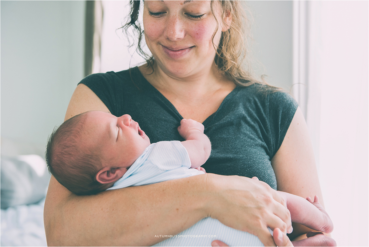 Mom Smiling at Newborn in Her Arms